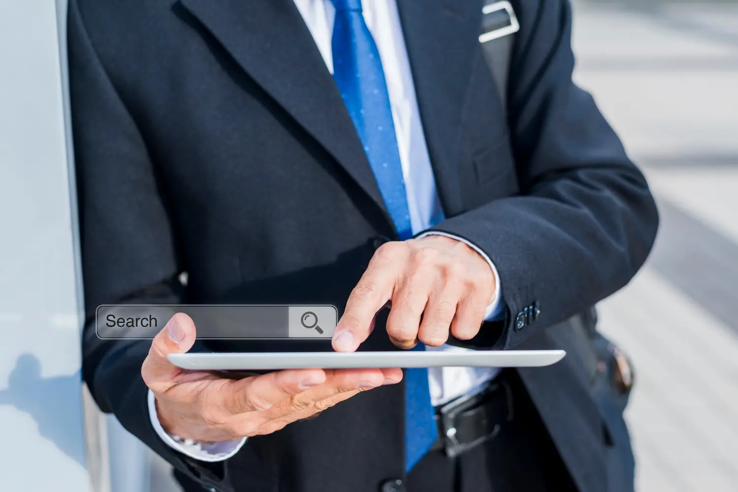 Close-up of a business professional using a tablet with a visible search bar, representing online search, digital services, or finding information on a mobile device.